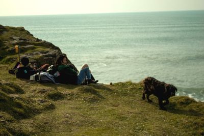 People sitting on beach by sea against sky