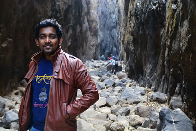 Young man standing against rock