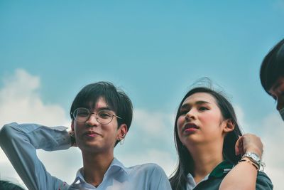 Low angle view portrait of friends standing against sky