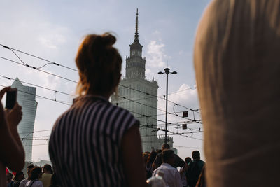 Rear view of people standing against buildings in city