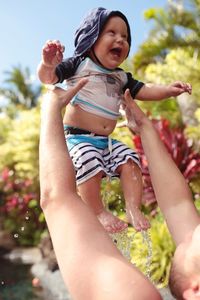 Full length of happy girl playing in water against sky