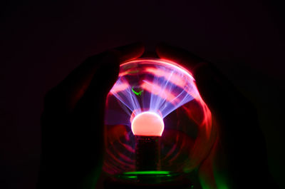 Close-up of hand holding illuminated light against black background