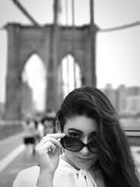 Portrait of young woman holding sunglasses outdoors