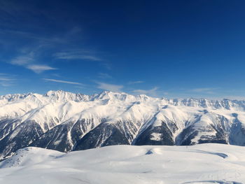 Scenic view of snowcapped mountains against blue sky