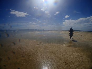 Woman walking on beach against sky