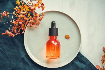Vitamin c serum in a bottle with a pipette on a round dish. the concept of anti-acid skin care.