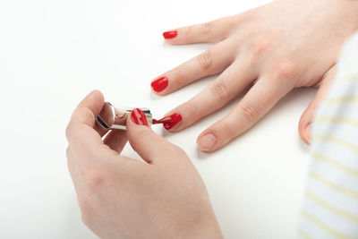 Young woman applies varnish on her nails.