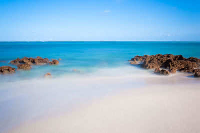 Peaceful beach with water access between reefs. long exposure, deep blues and turquoise waters