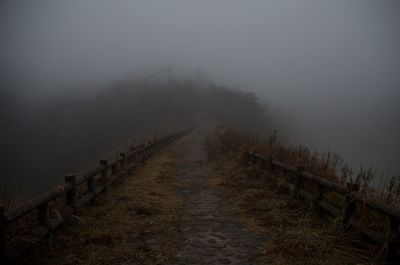 Fence on land against sky during foggy weather