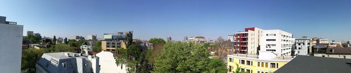 Rear view of buildings in city against clear blue sky