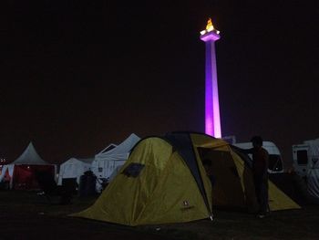 Tent in illuminated building against sky at night