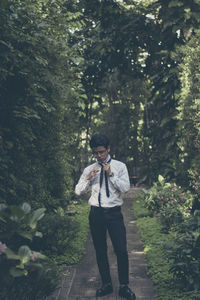 Young man wearing necktie while standing amidst trees in park