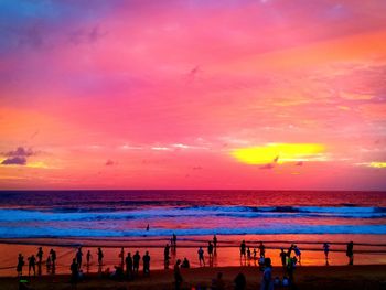 People on beach against sky during sunset