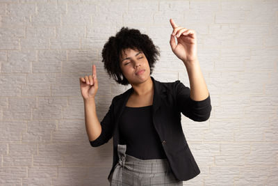 Portrait of young woman standing against wall