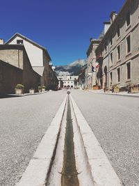 Road amidst buildings in city against clear sky