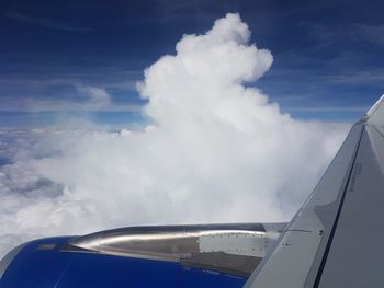 Close-up of airplane wing against cloudy sky