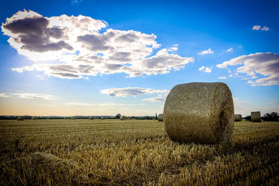 Hay bales on field against sky