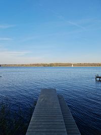 Pier over lake against blue sky