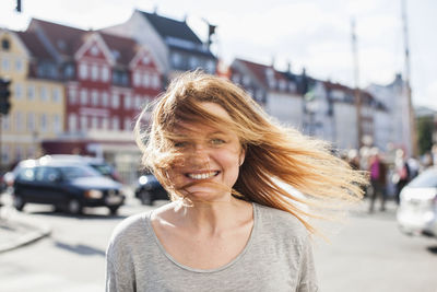 Portrait of happy woman with windswept hair on city street
