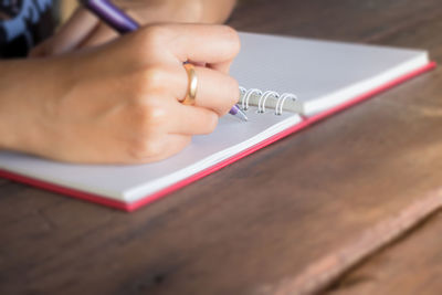 Close-up of woman writing in note book