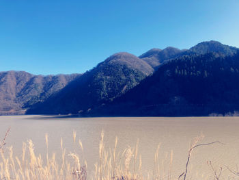 Scenic view of lake and mountains against clear blue sky