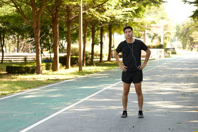 Full length portrait of young man on road against trees