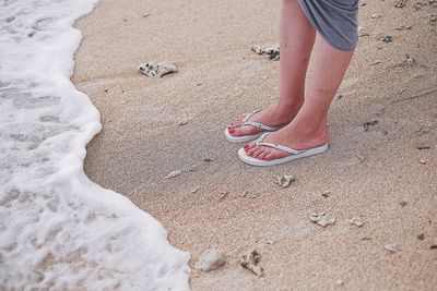 Low section of man standing on sand