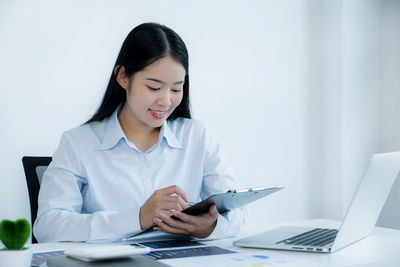 Young woman using mobile phone while sitting on table