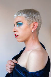 Portrait of young transgender man with makeup looking away