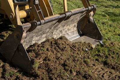 Clearing and leveling a private land plot. yellow excavator driving earth in a wide bucket