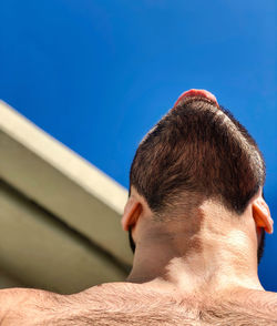 Rear view of young man against blue sky