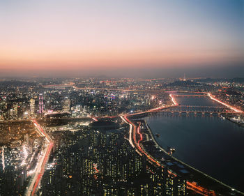 High angle view of illuminated bridge and buildings against sky at night