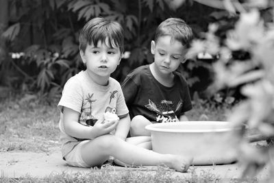 Brothers eating food while sitting on land