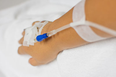 Cropped hand of woman with iv drip in hospital