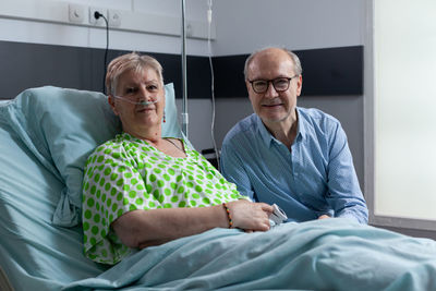 Portrait of smiling family sitting on bed at home