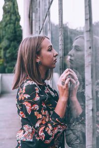 Side view of young woman looking through window