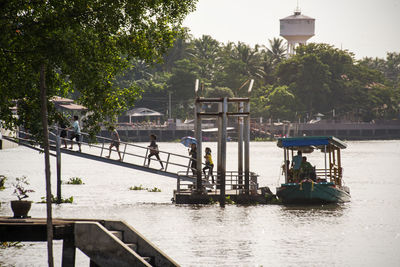 People on boat in river against trees