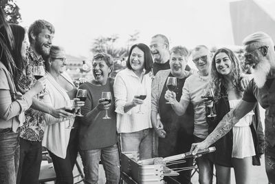 Group of people with wineglasses standing at backyard