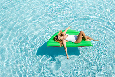 High angle view of siblings lying down in swimming pool