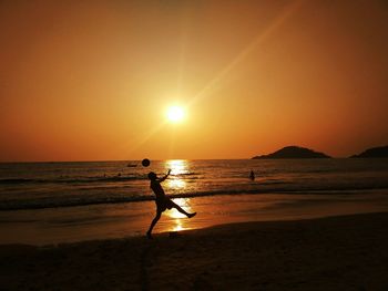 Silhouette person on beach against sky during sunset