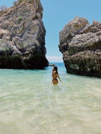 Rear view of woman in sea against mountain
