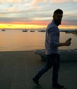 Man standing by sea against sky during sunset