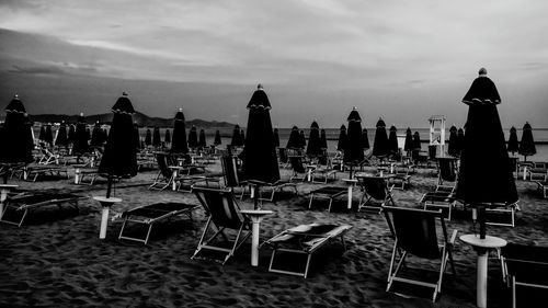 Chairs and table at beach against sky