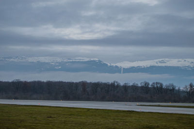 Scenic view of field by lake against sky