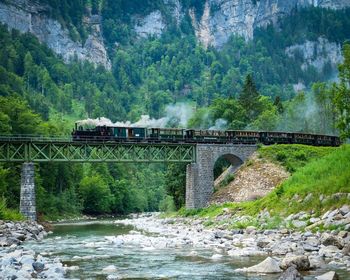 Train on railway bridge against mountain