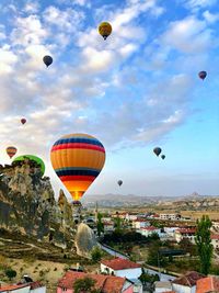 Hot air balloons flying in city against sky