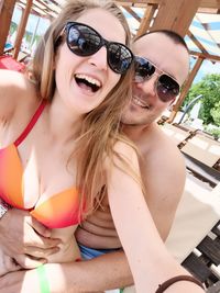 Portrait of smiling couple wearing sunglasses embracing outdoors