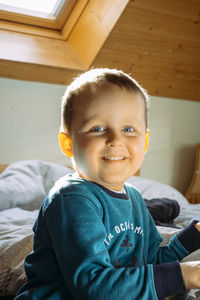 Portrait of cute boy sitting on bed at home