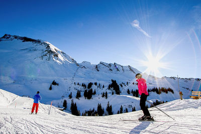 Tourists on mountain against cloudy sky