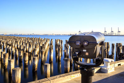 Close-up of coin-operated binoculars by sea against clear sky